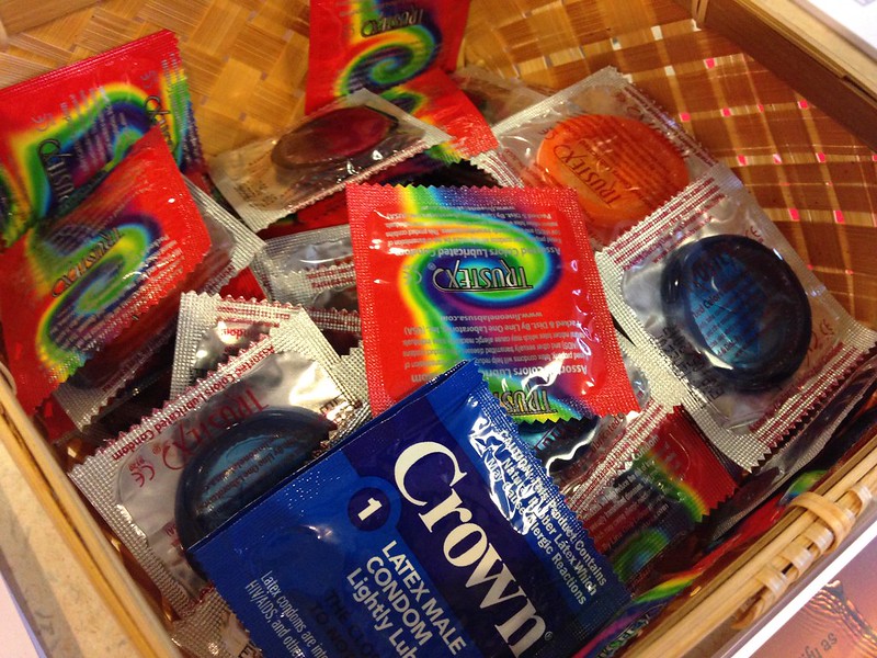 An open drawer filled with colourful condoms in their packaging.