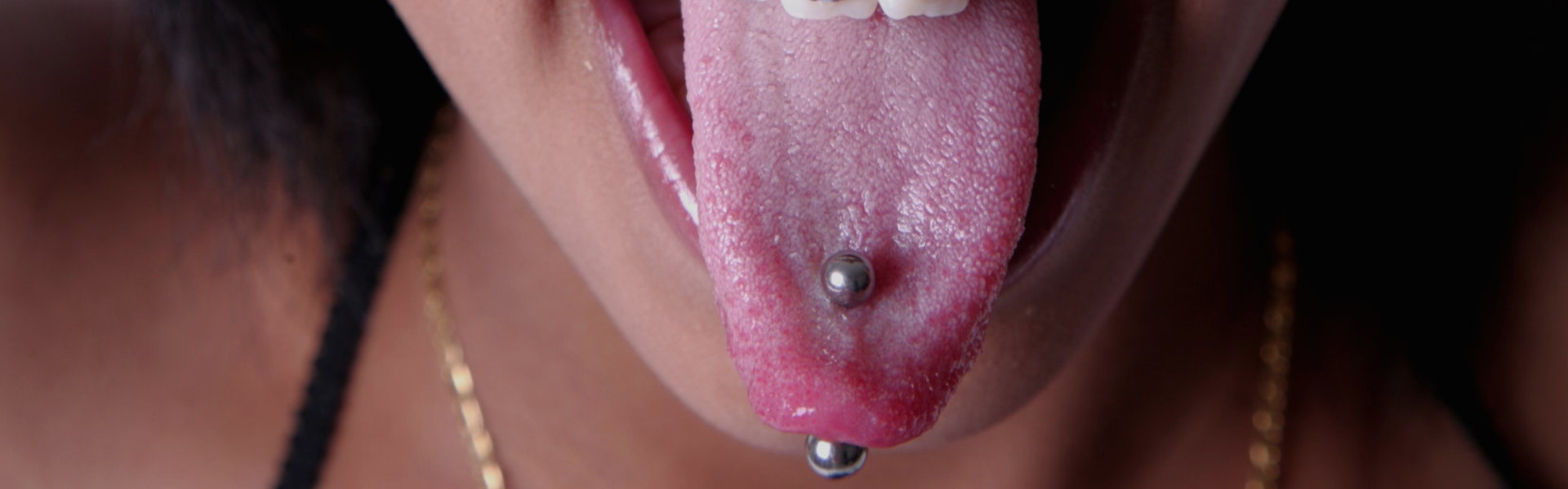 A close-up shot of a pierced tongue that a young woman is sticking out playfully.