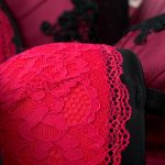 A close-up shot of multiple fancy lace bras. Some are scarlet, others are a purplish red, some are black.